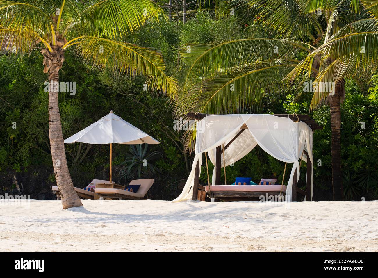 Weiße Stranddächer und Sonnenschirm bei Sonnenuntergang. Luxuriöse Strandzelte im luxuriösen Strandresort. Sommer-Strandkonzept, unbeschwert, Erholung am Meer, Niemand auf Stockfoto