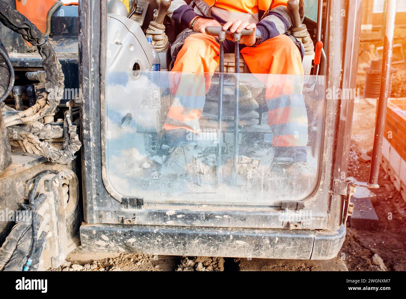 Maschinenführer, der den Bagger auf der Baustelle bedient Stockfoto