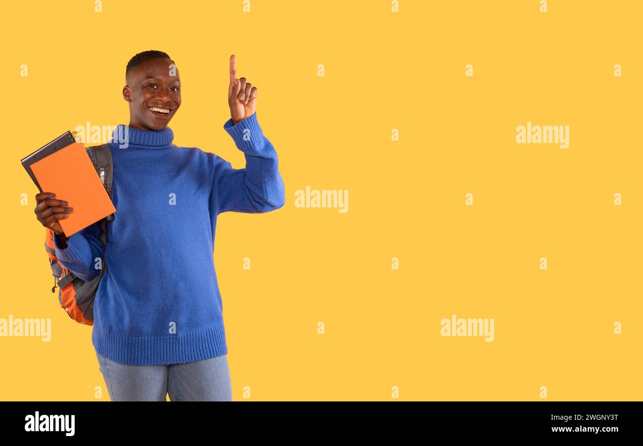 Frau in einem blauen Pullover mit Notizbüchern und Rucksack, der ihren Zeigefinger als Idee auf gelbem Hintergrund hebt, reist. Holen Sie sich die Idee. Journey, educ Stockfoto