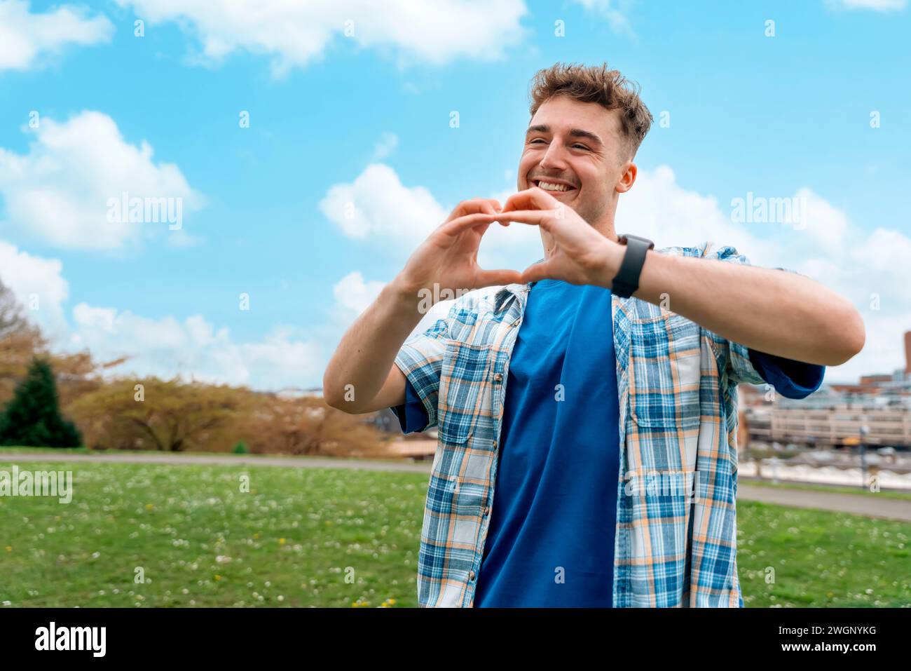 Ein junger Mann mit herzförmigen Händen im Park ‌ Sommertag Fall in Love Konzept Stockfoto