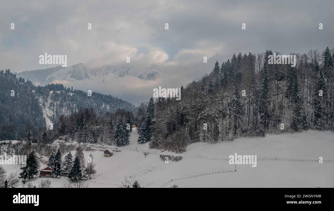 Winterlandschaft des Dorfes CHATEAU D'OEX. Kanton Waadt, Schweiz. Berg, Himmel, Wald und Schweizer Chalet. Stockfoto