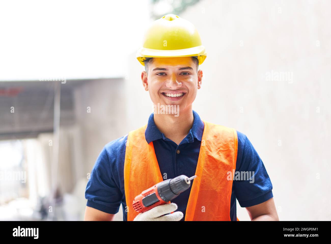 Lächelnde junge männliche Wehen, die ein Elektrowerkzeug halten Stockfoto