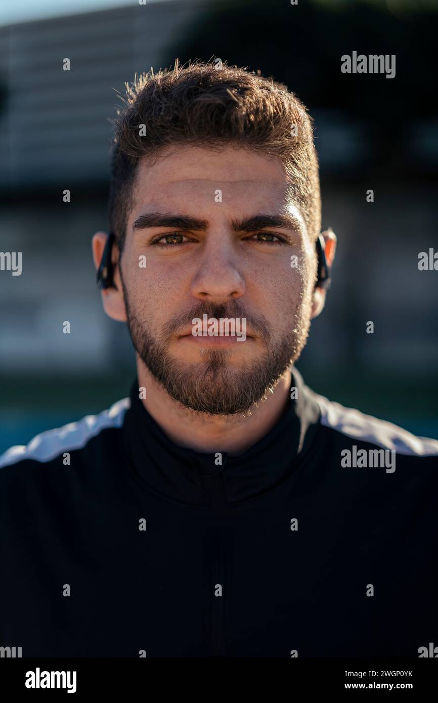 Eine Nahaufnahme eines Mannes, der ein schwarzes Hemd und Ohrstöpsel trägt Stockfoto