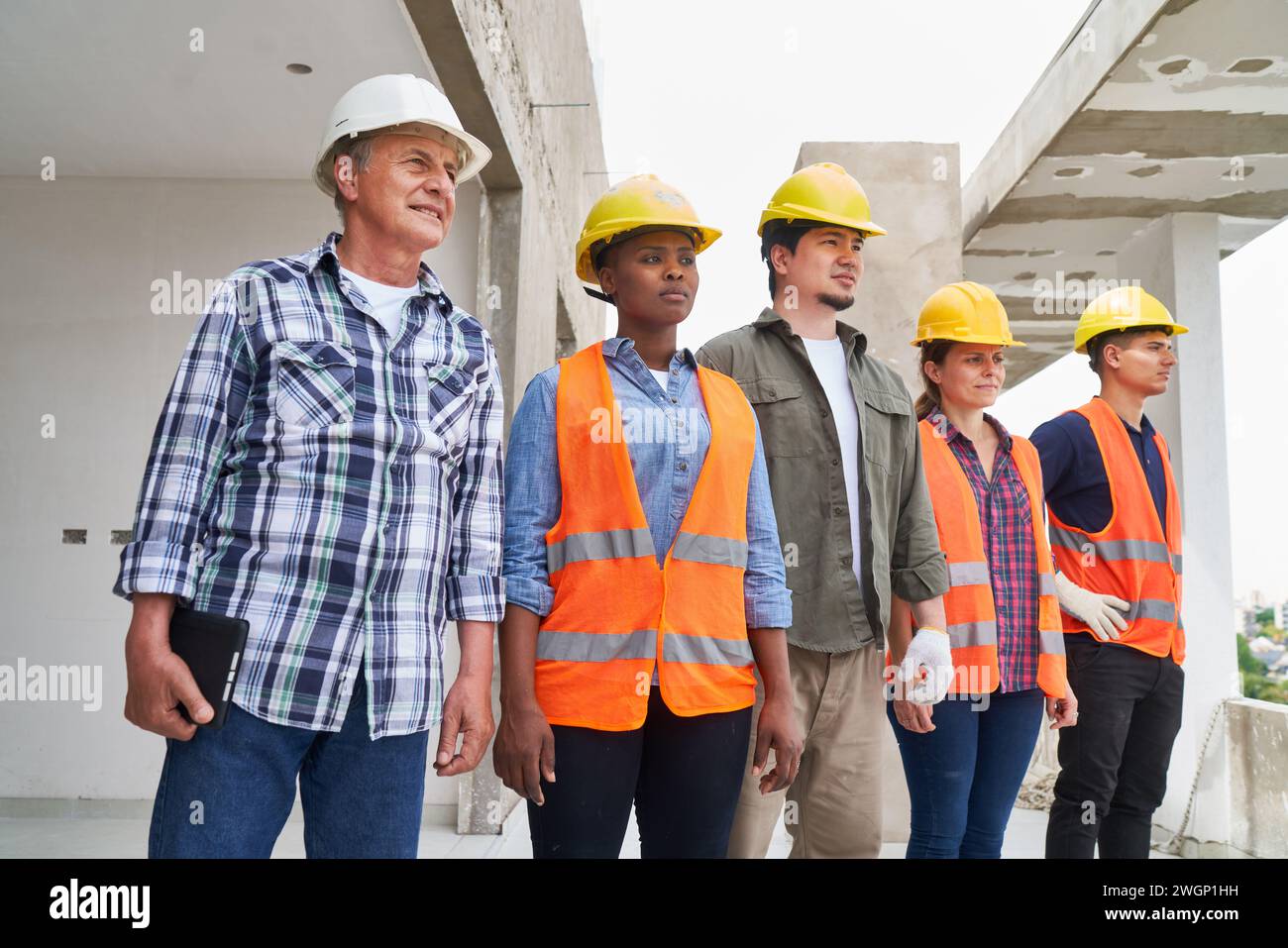 Selbstbewusstes Team von Arbeitern in Arbeitskleidung, das wegblickt Stockfoto