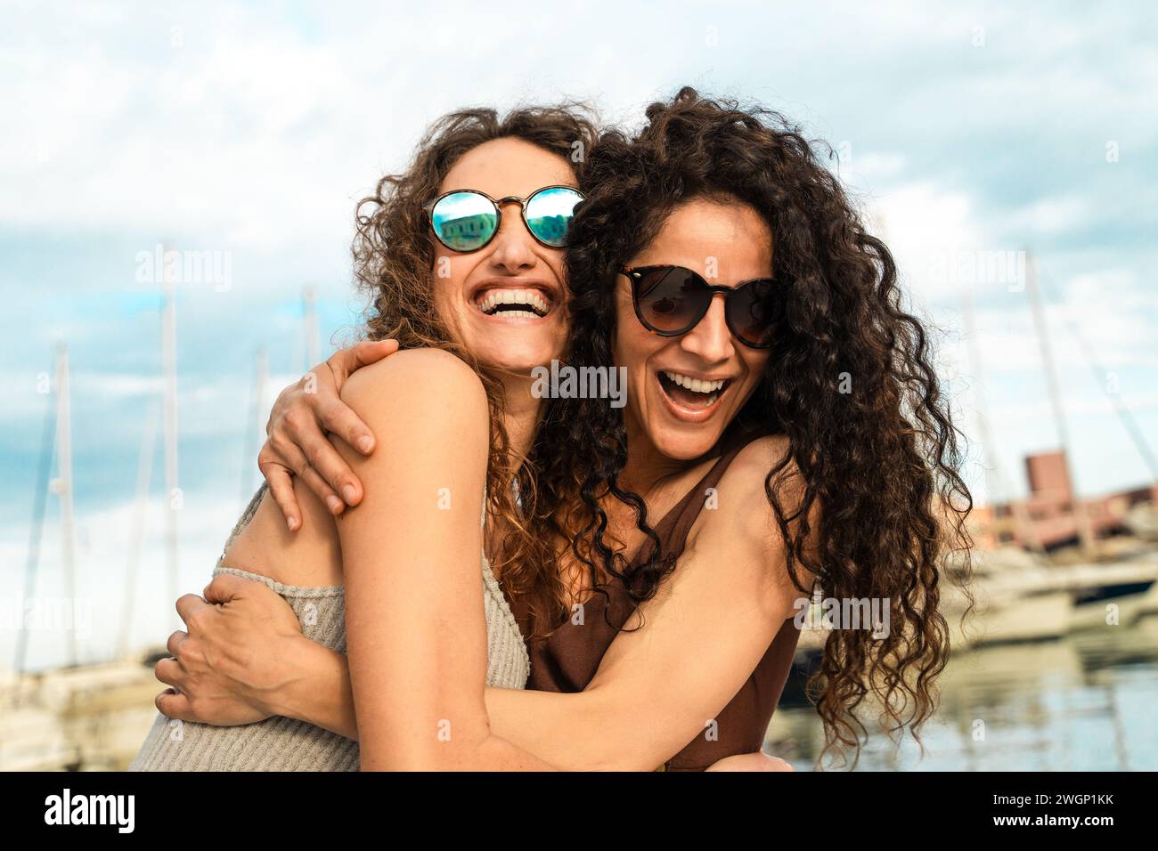Zwei enge Freunde teilen sich eine Umarmung und ein Lachen auf einer Yacht und schätzen den Moment. Stockfoto