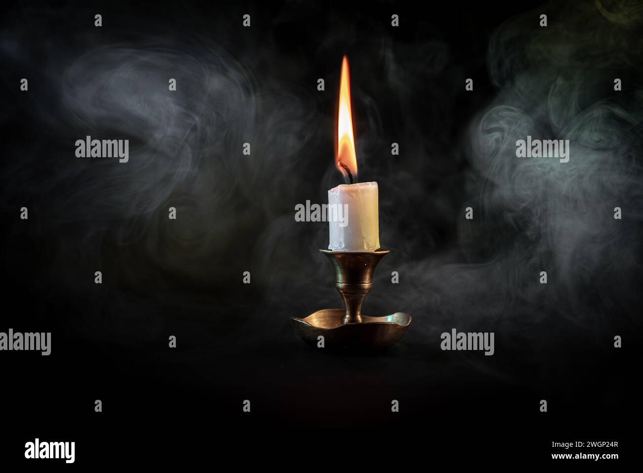 Eine Nahaufnahme des Dampfes, der von einer beleuchteten Kerze auf dunklem Hintergrund aufsteigt Stockfoto
