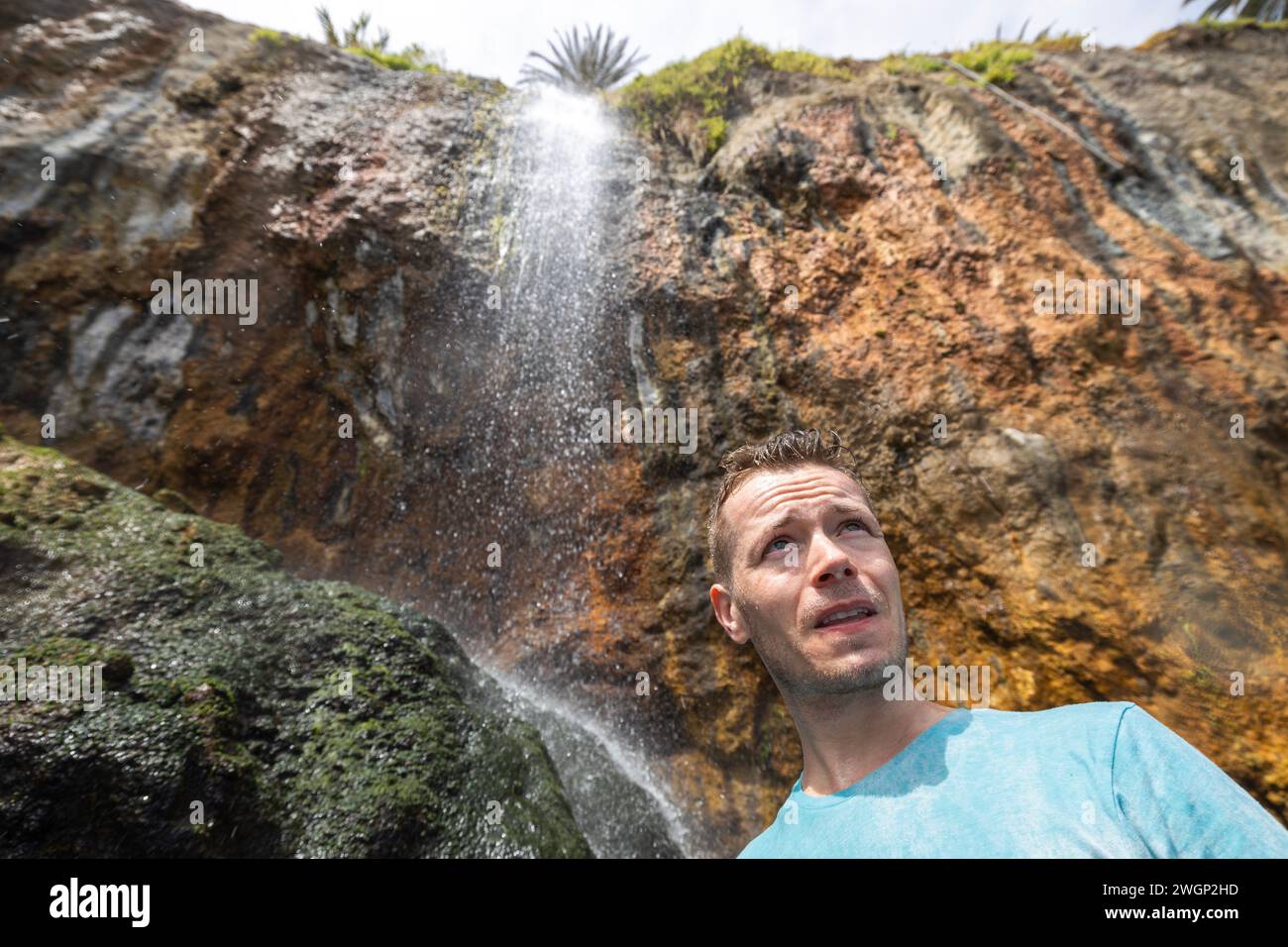 Porträt eines Menschen, der unter dem Wasserfall auf Teneriffa, Kanarischen Inseln, Spanien steht. Stockfoto