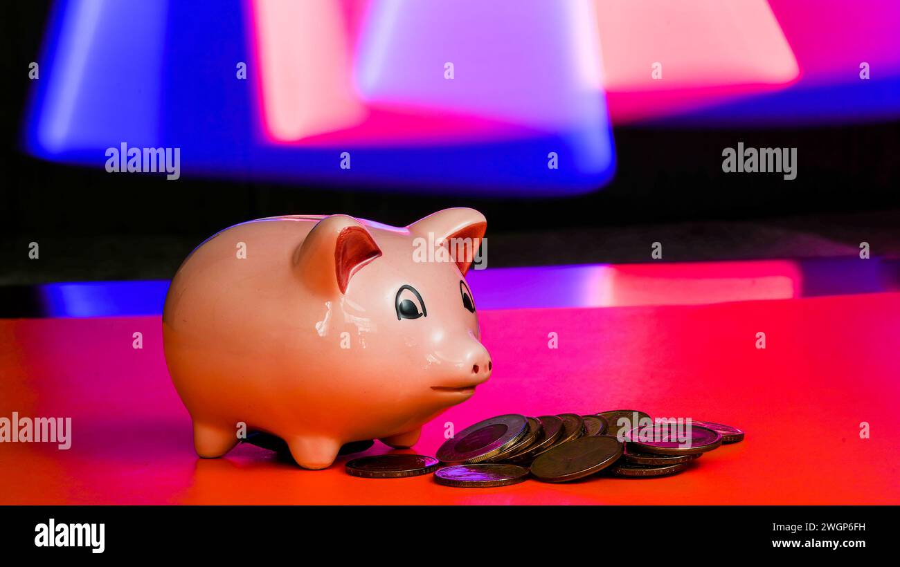 Rosafarbene Schweinebank mit Münzen und farbenfrohem Hintergrund Stockfoto