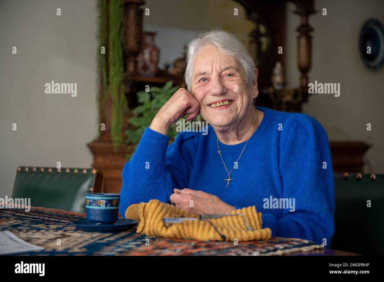 Elderley-Dame strickt an ihrem Esstisch Stockfoto