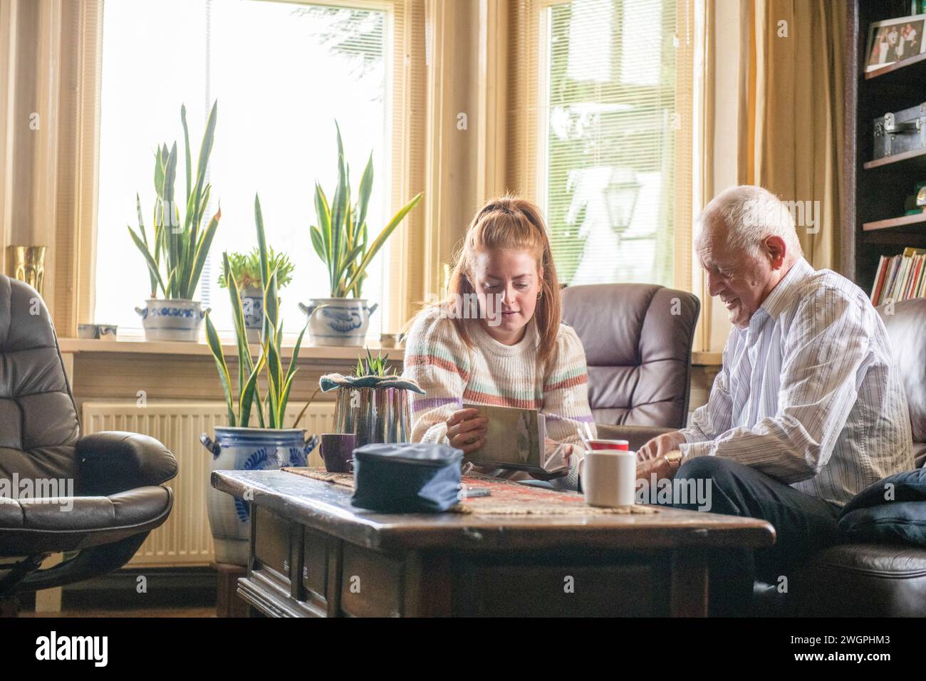 Die Großtochter sieht sich alte Familienfotos mit Opa an Stockfoto