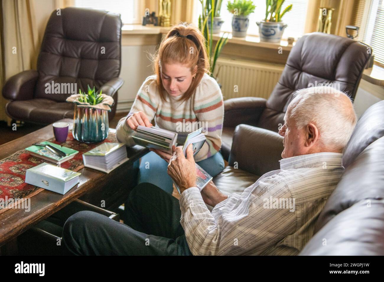 Die Großtochter sieht sich alte Familienfotos mit Opa an Stockfoto