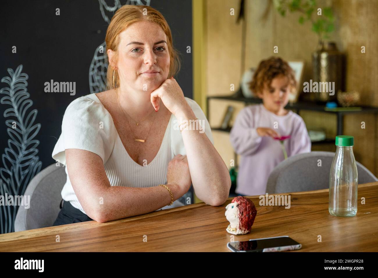 Porträt einer schönen Ingwerfrau, die an ihrem Tisch sitzt Stockfoto