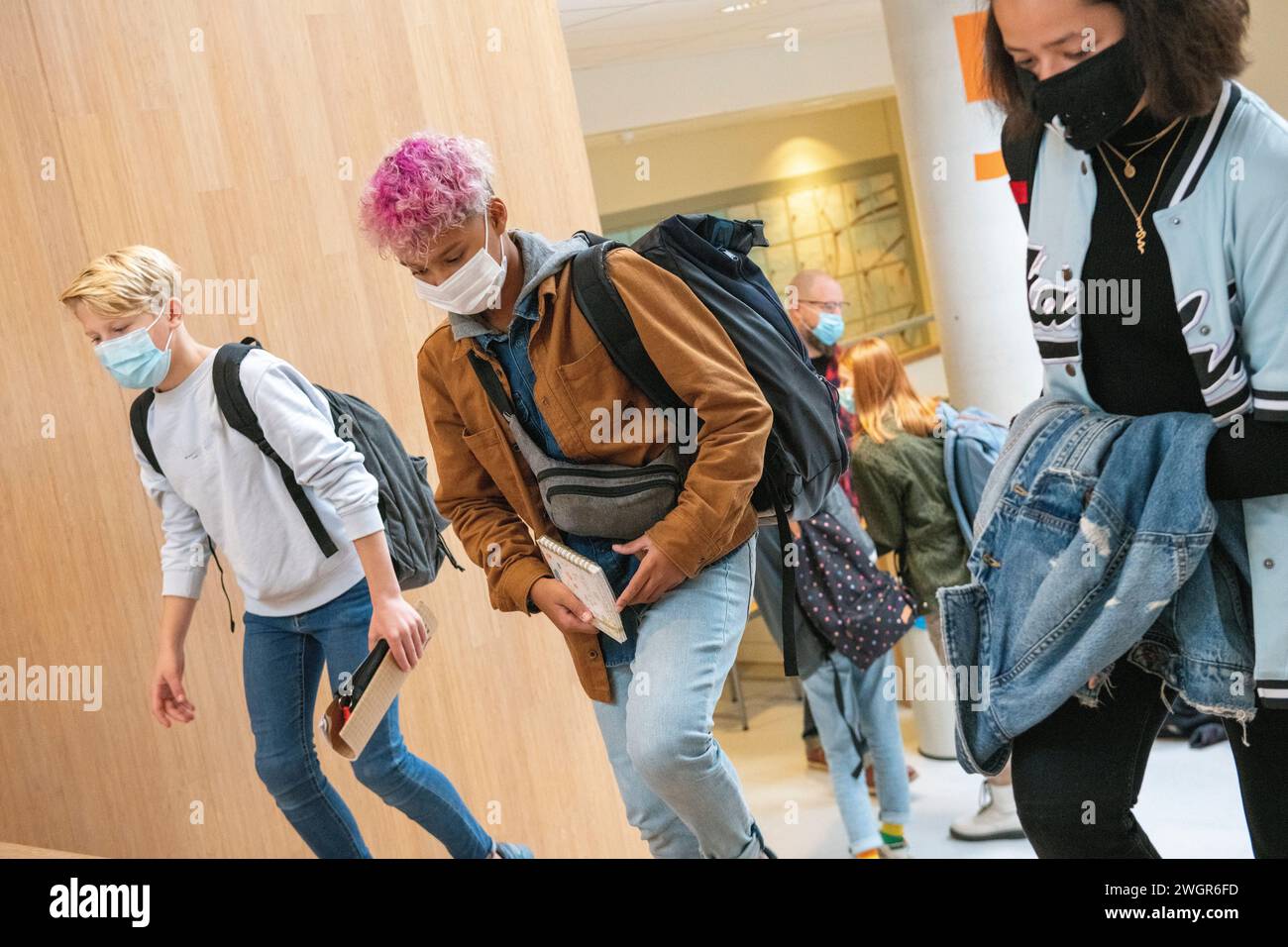 Teenagerschüler mit gemischter Rasse, die durch die Schule zu ihrer nächsten Klasse laufen Stockfoto