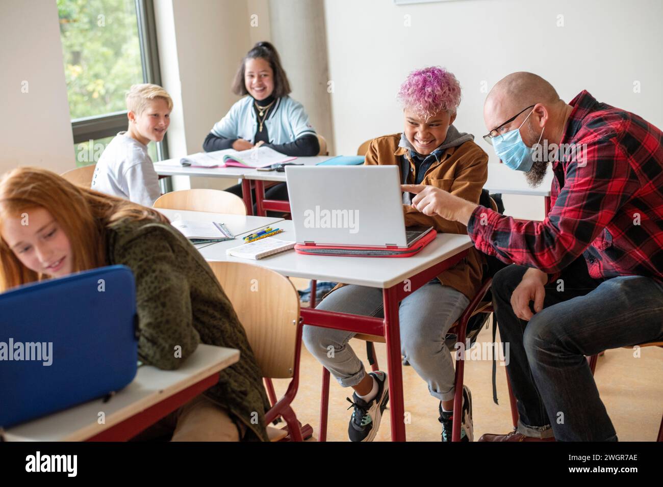 Junge Teenager-Schüler, die mit Hilfe ihres Lehrers von ihrem Laptop aus arbeiten Stockfoto