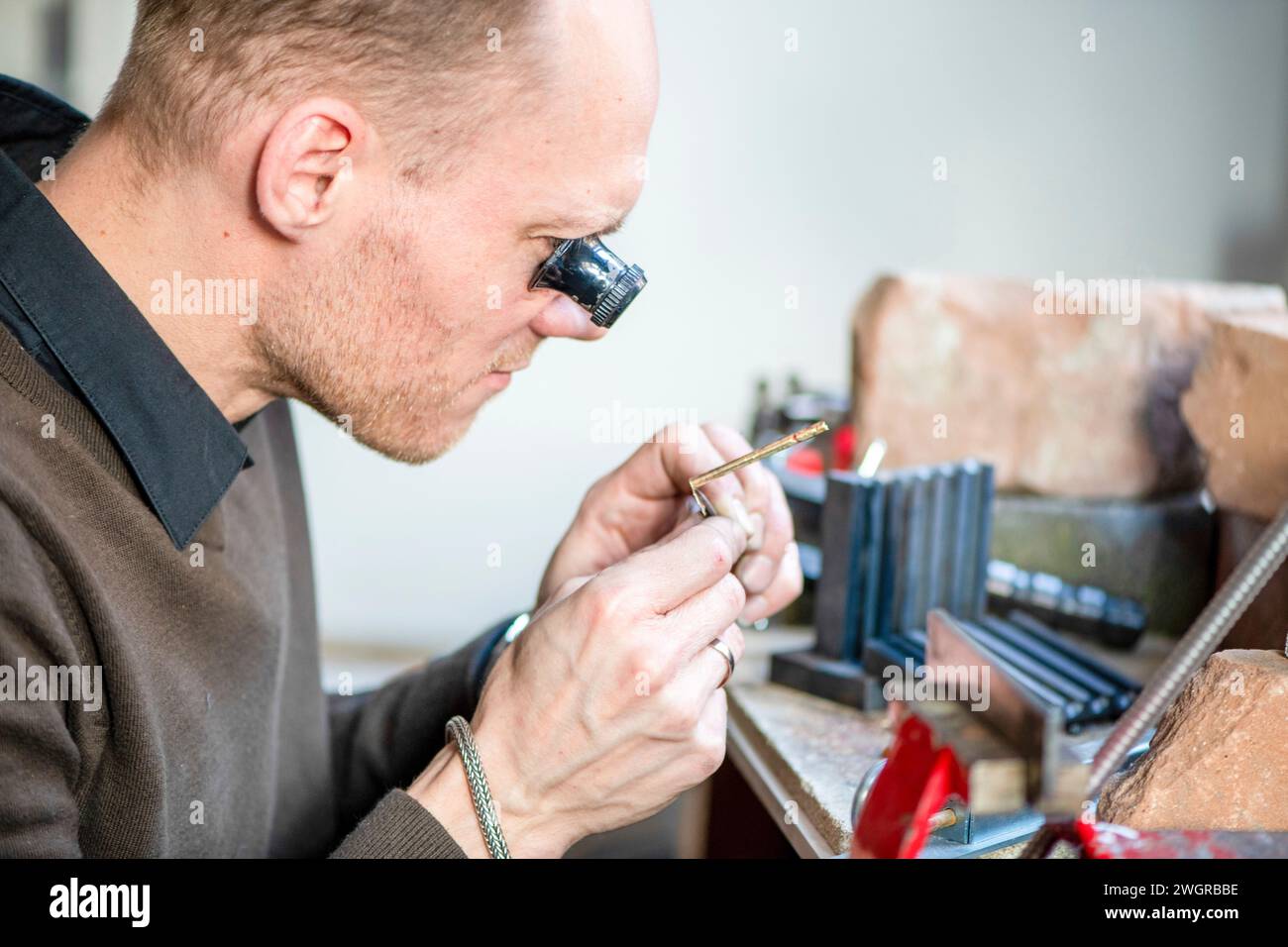 Uhrenmacher repariert eine klassische Uhr, einen authentischen Arbeitsplatz. Verwendung eines Monokels und kleiner, winziger Werkzeuge für Reparaturen Stockfoto