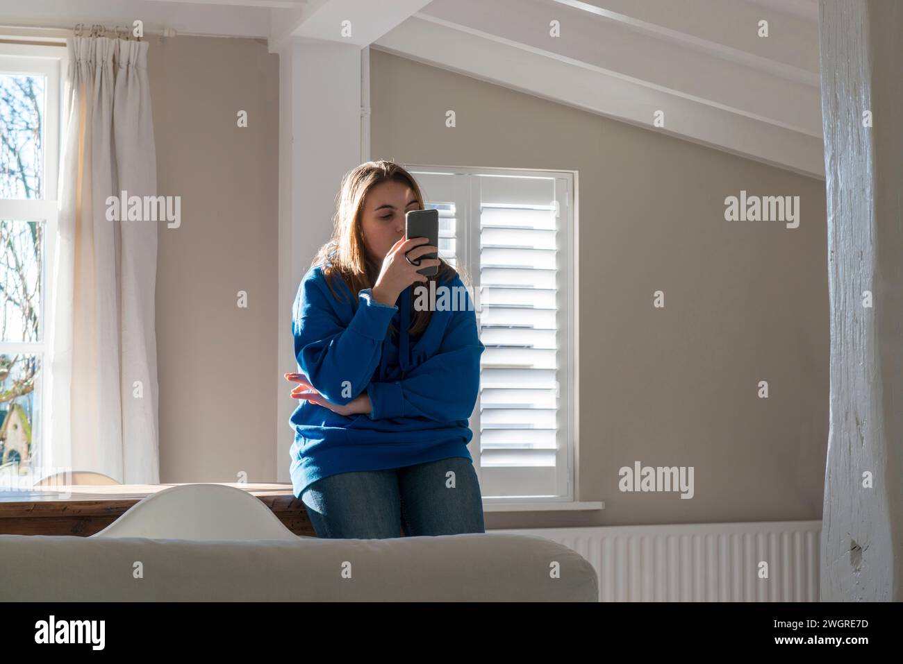 Mürrische Teenagerin, die sich auf ihr Handy konzentriert Stockfoto