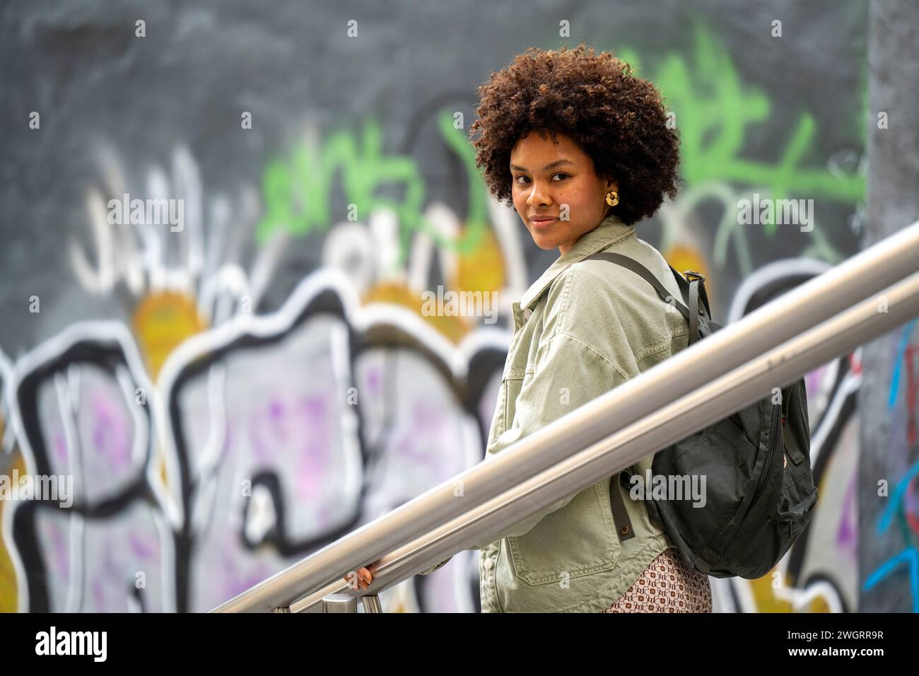 Trendige junge Afrikanerin mit gemischter Rasse, die glücklich durch die Stadt läuft. Stockfoto