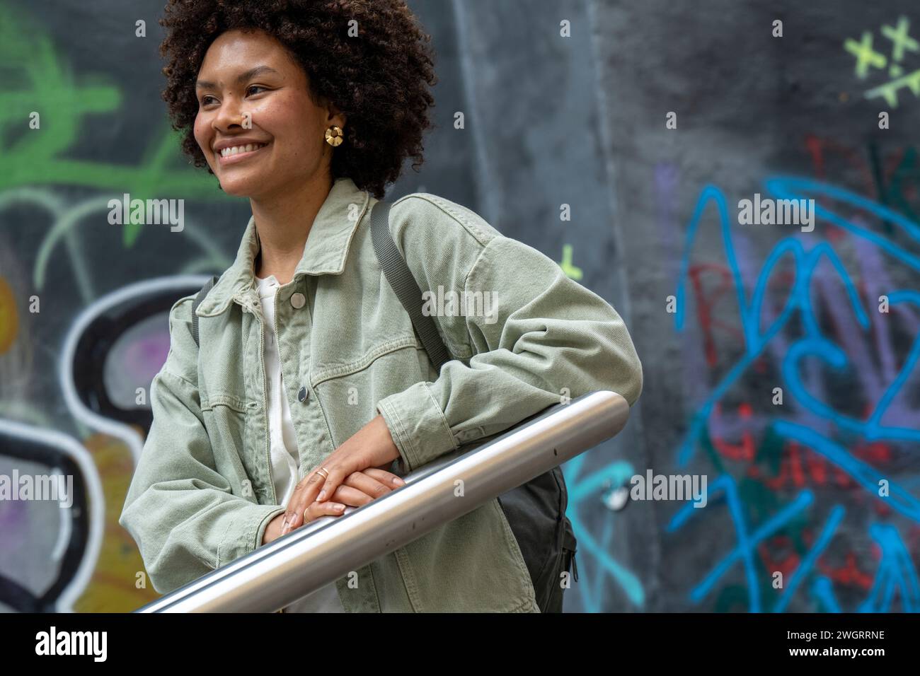 Trendige junge Afrikanerin mit gemischter Rasse, die glücklich durch die Stadt läuft. Stockfoto