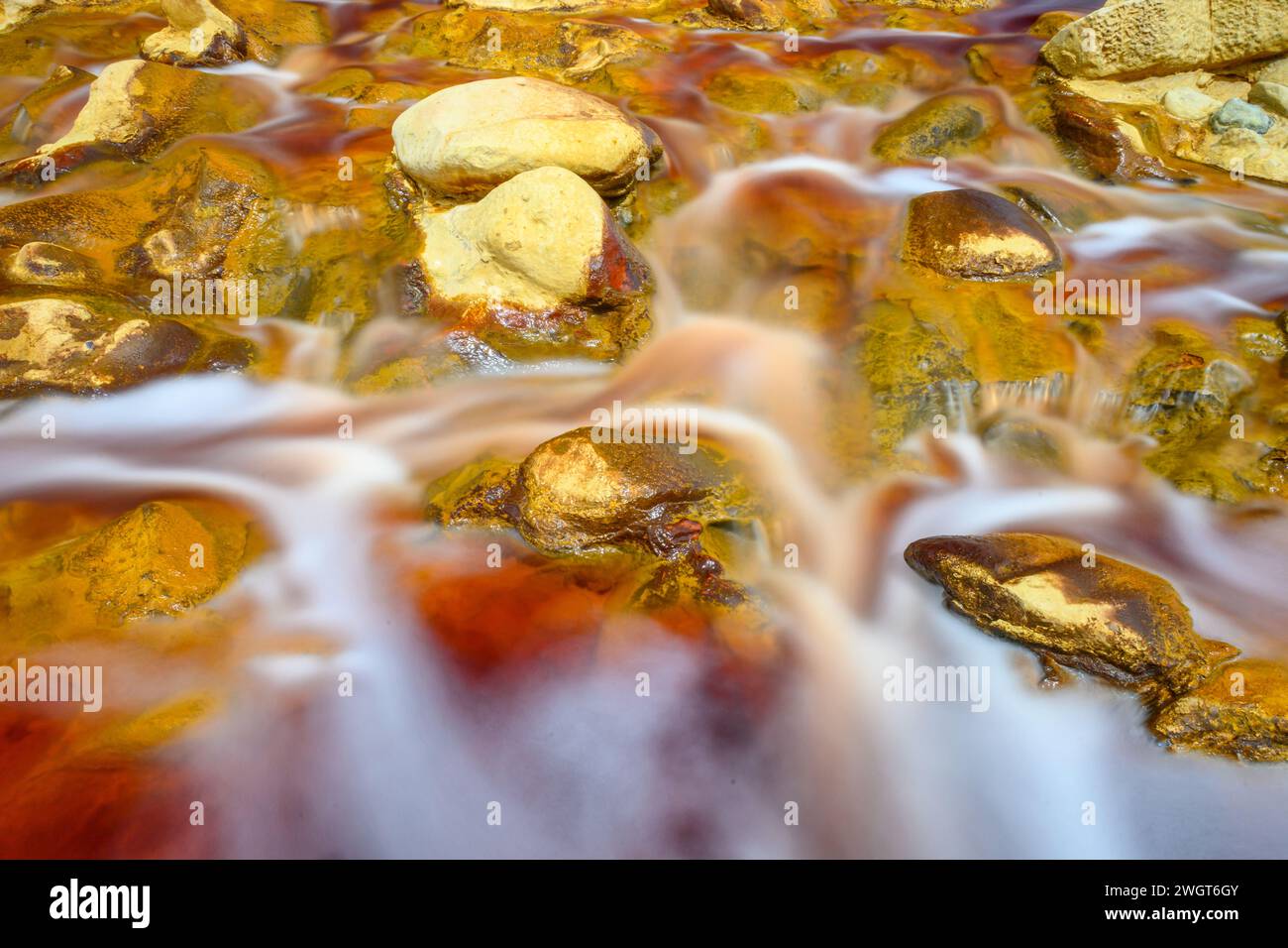 Schäumendes Wasser rauscht über die bunten, eisenbeladenen Felsen im Rio Tinto Stockfoto