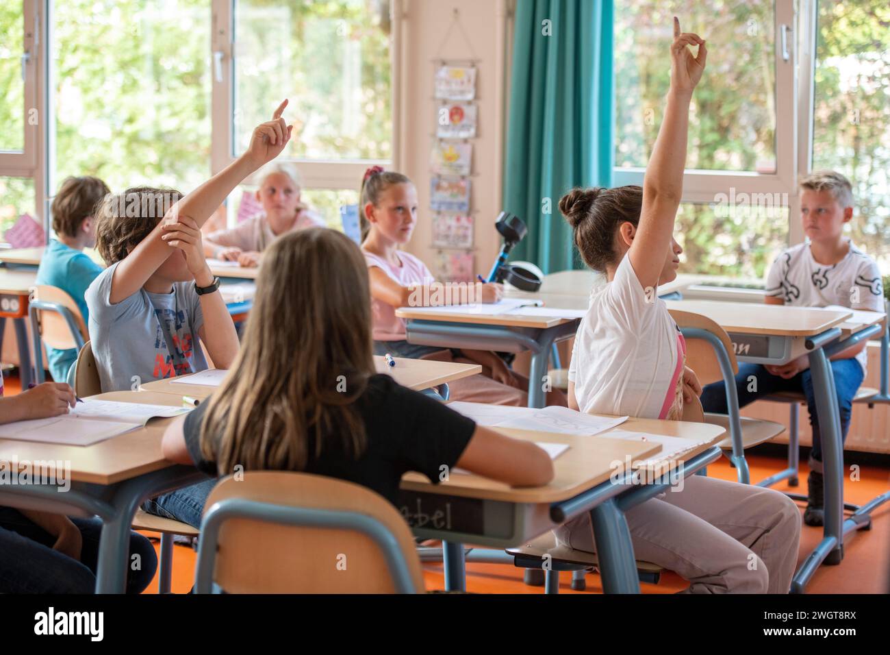 Gruppe junger Schüler in der Klasse, die ihre Hände hochlegen, um eine Frage an den Lehrer zu stellen Stockfoto