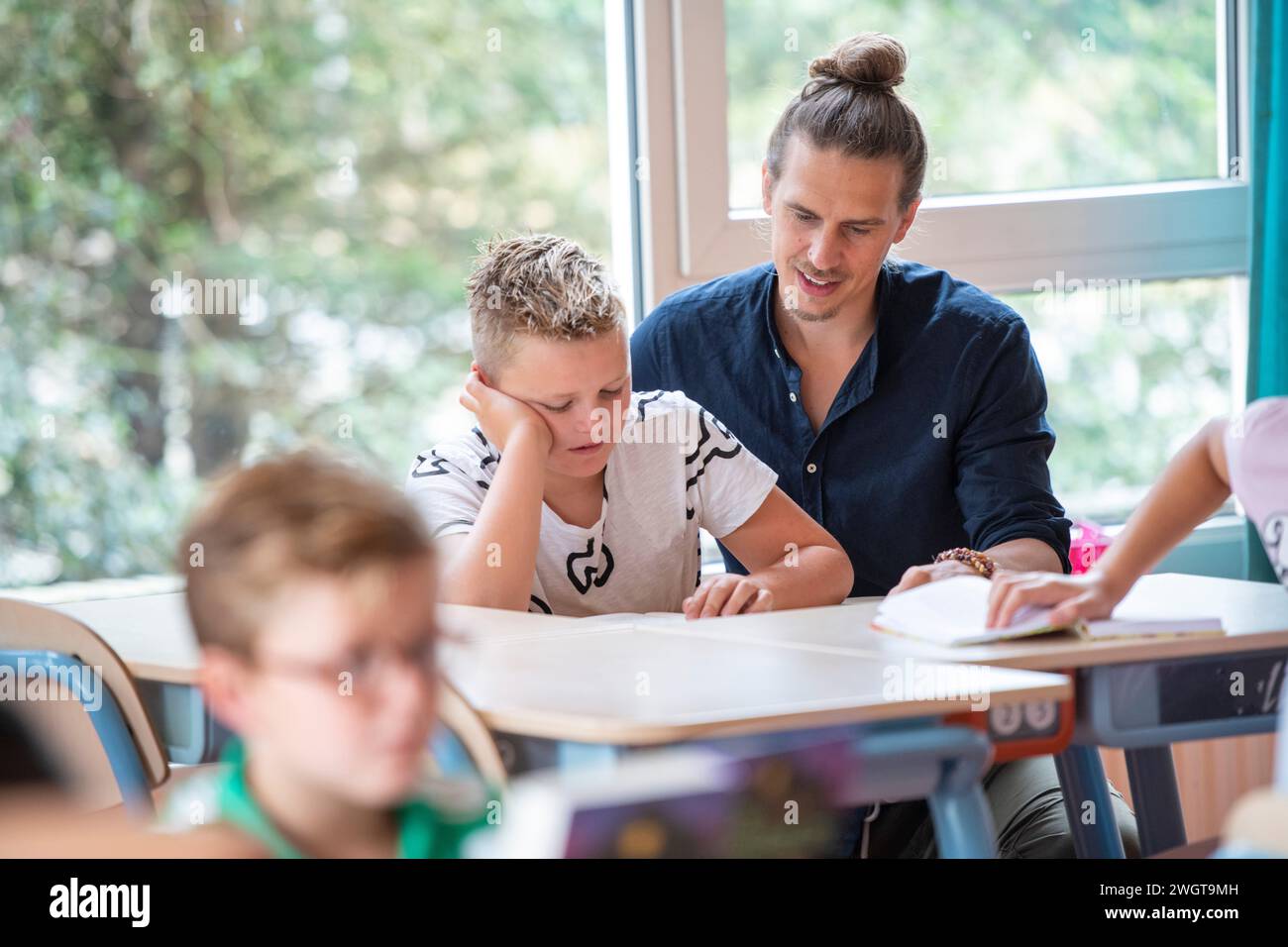 Ein Lehrer hilft einem Jungen in der Klasse mit einem Problem, das er hat Stockfoto