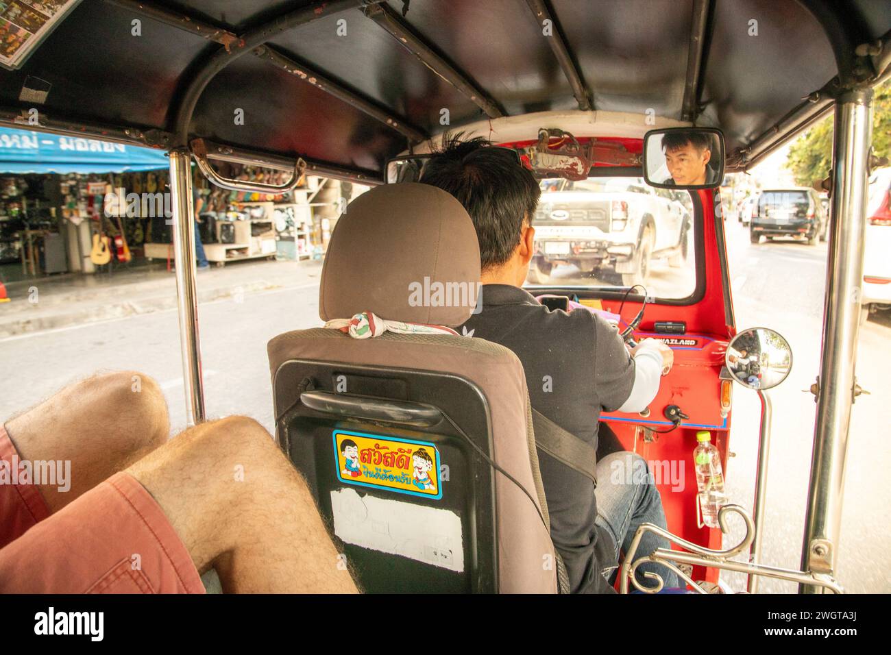 Touristen, die im hinteren Teil des Tuk Tuk Taxis durch Chiang Mai im Norden Thailands fahren Stockfoto