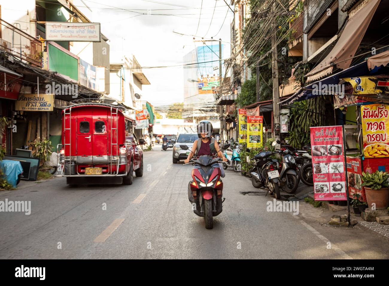 Frau mittleren Alters Alleinreisender, der einen Mietroller durch die Seitenstraßen von Chiang Mai fährt. Nordthailand Stockfoto