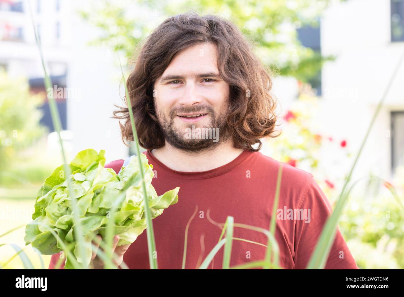 Junger Mann mit Salat im Garten in der Stadt Stockfoto