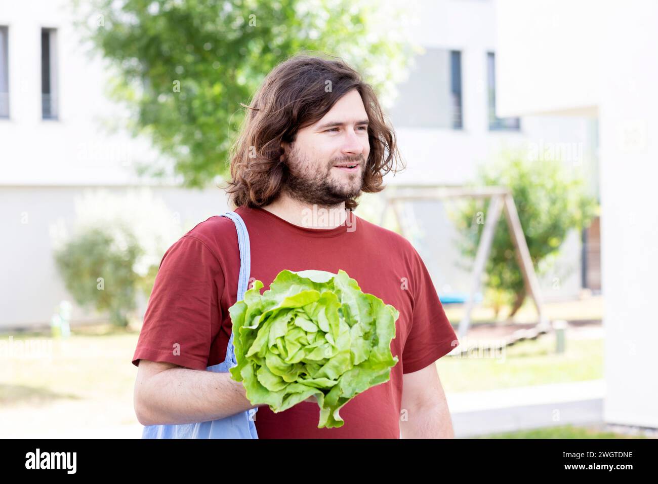 Junger Mann mit Salat und Tüte, der nach Hause geht Stockfoto