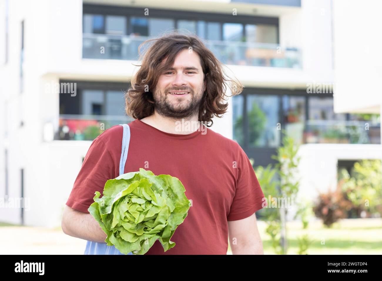 Junger Mann mit einer Tasche, der einen Salat verkauft und in der Stadt nach Hause geht Stockfoto