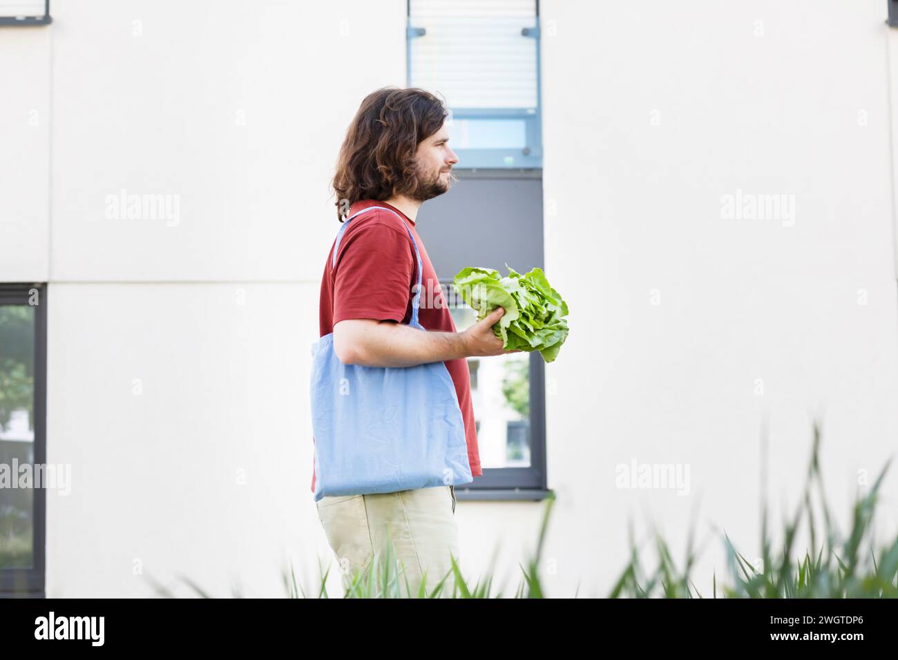 Junger Mann mit einer Tasche, der einen Salat verkauft und in der Stadt nach Hause geht Stockfoto
