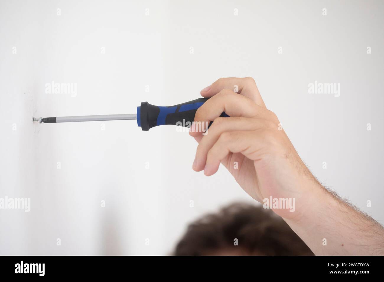 Die Hand eines Mannes, der eine Schraube mit einem Schraubenzieher einsetzt Stockfoto