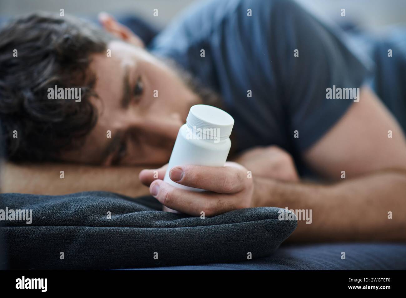 Verzweifelter Mann, der Pillen während depressiver Episode mit Selbstverletzung hält, geistiges Gesundheitsbewusstsein Stockfoto