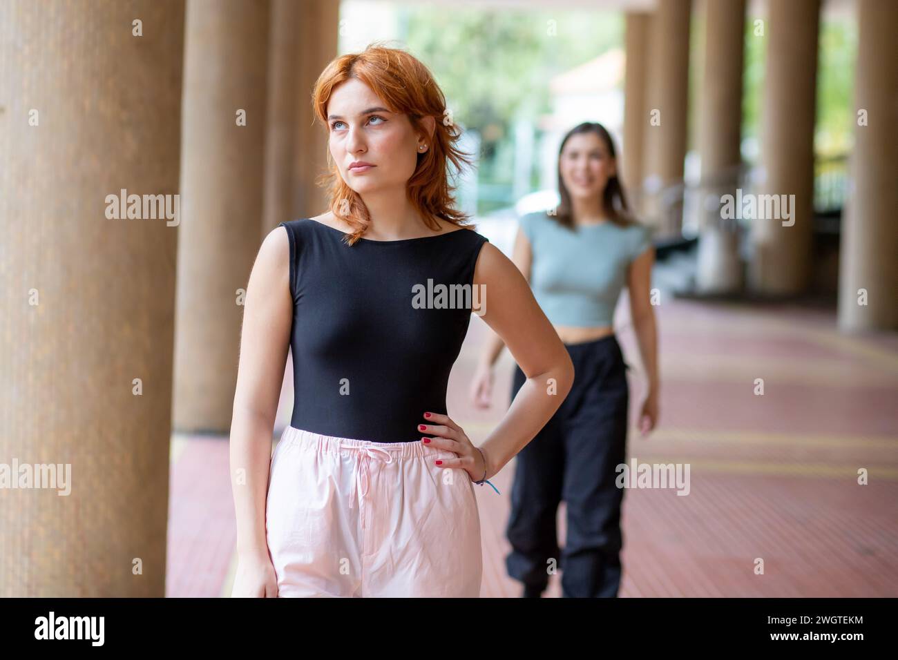 Eine junge Frau, die aufgeregt ist, dass sich hinter ihr eine Freundin nähert Stockfoto