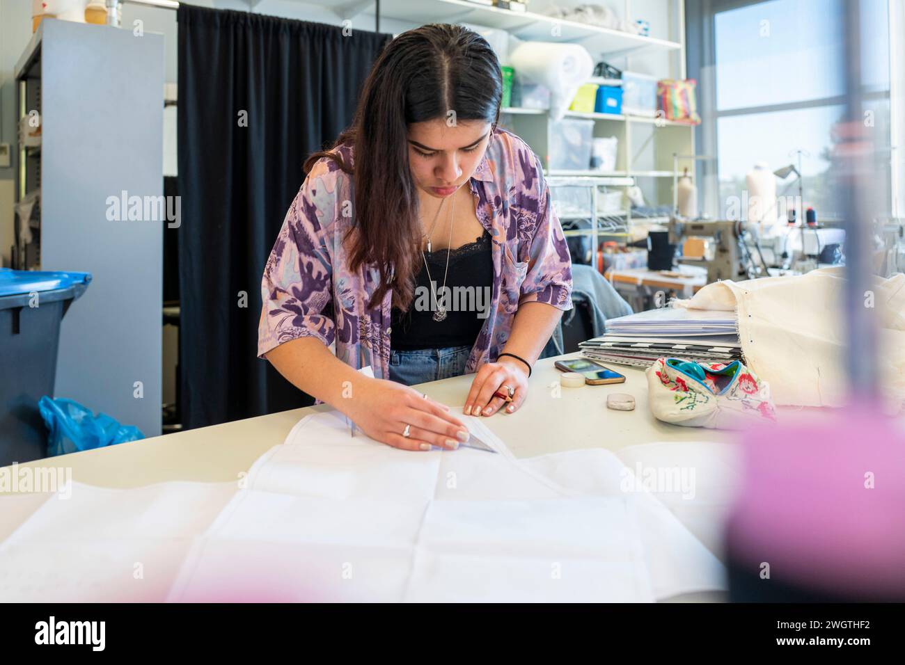 Modedesignerin, die in ihrer Werkstatt an Stoffdesigns arbeitet. Konzentration auf Muster und Design Stockfoto