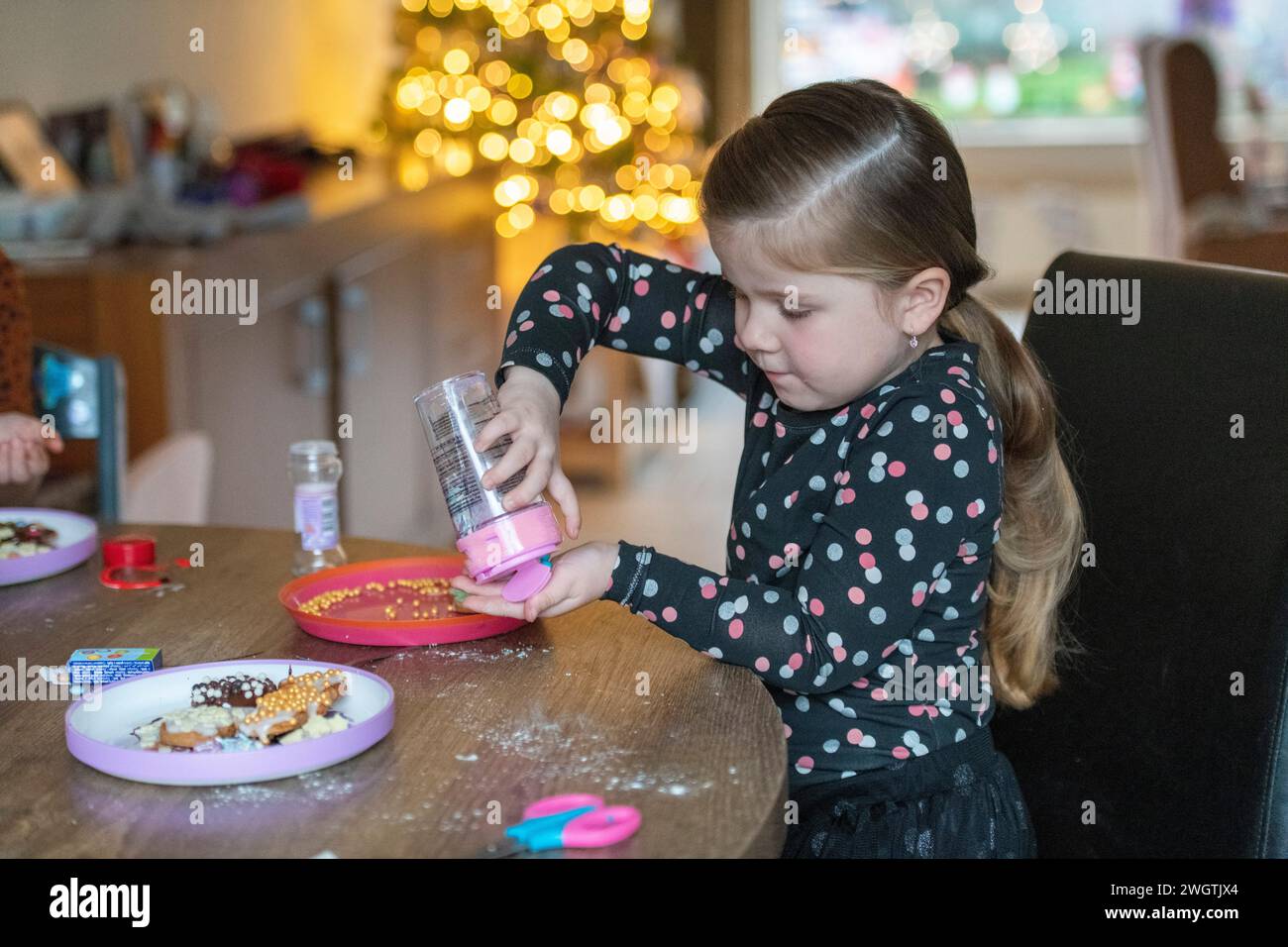 Ein junges Mädchen, das mit Streuseln an ihrem Esstisch sitzt Stockfoto