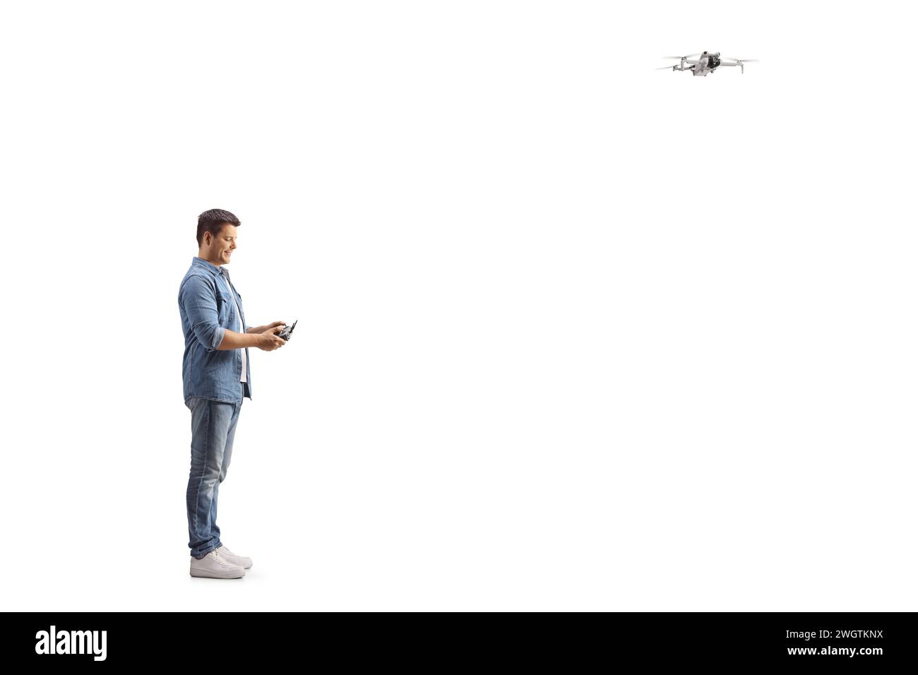Ein Mann, der eine Drohne fliegt und auf den ferngesteuerten Cotroller auf weißem Hintergrund blickt Stockfoto