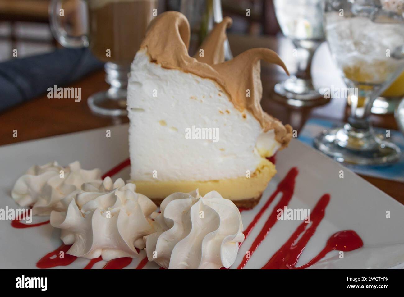 Key Lime Pie auf einem Teller mit Schlagsahne und rotem Niesel schneiden Stockfoto
