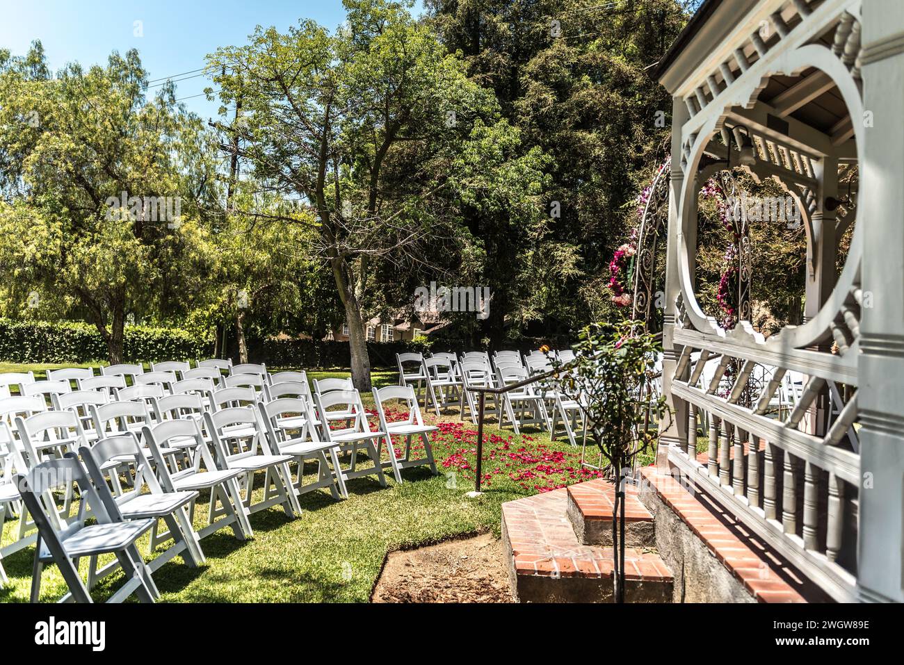 Hochzeitszeremonie im Freien mit weißen Sitzanordnungen und farbenfrohen roten Rosen Stockfoto