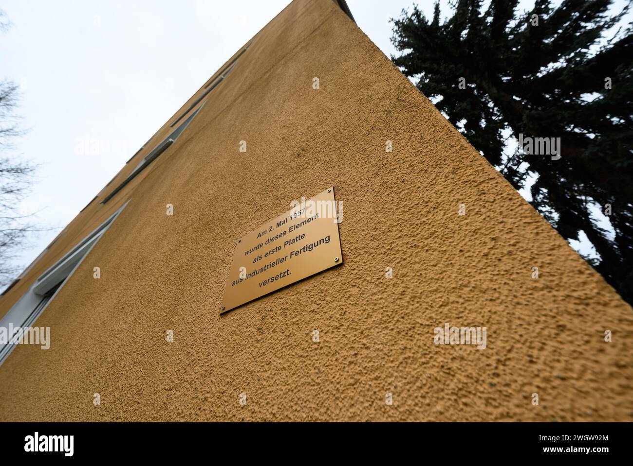 Hoyerswerda, Deutschland. Februar 2024. An der Fassade eines denkmalgeschützten Wohnblocks in der Konrad-Zuse-Straße im Wohnkomplex I (WK I) befindet sich ein Schild mit der Aufschrift „am 2. Mai 1957 wurde dieses Element als erste Platte aus der industriellen Produktion verlegt“. Der kommunale Wohnungsbauverband plant den Abriss von zwei Wohnblöcken im Stadtteil. Robert Michael/dpa/Alamy Live News Stockfoto