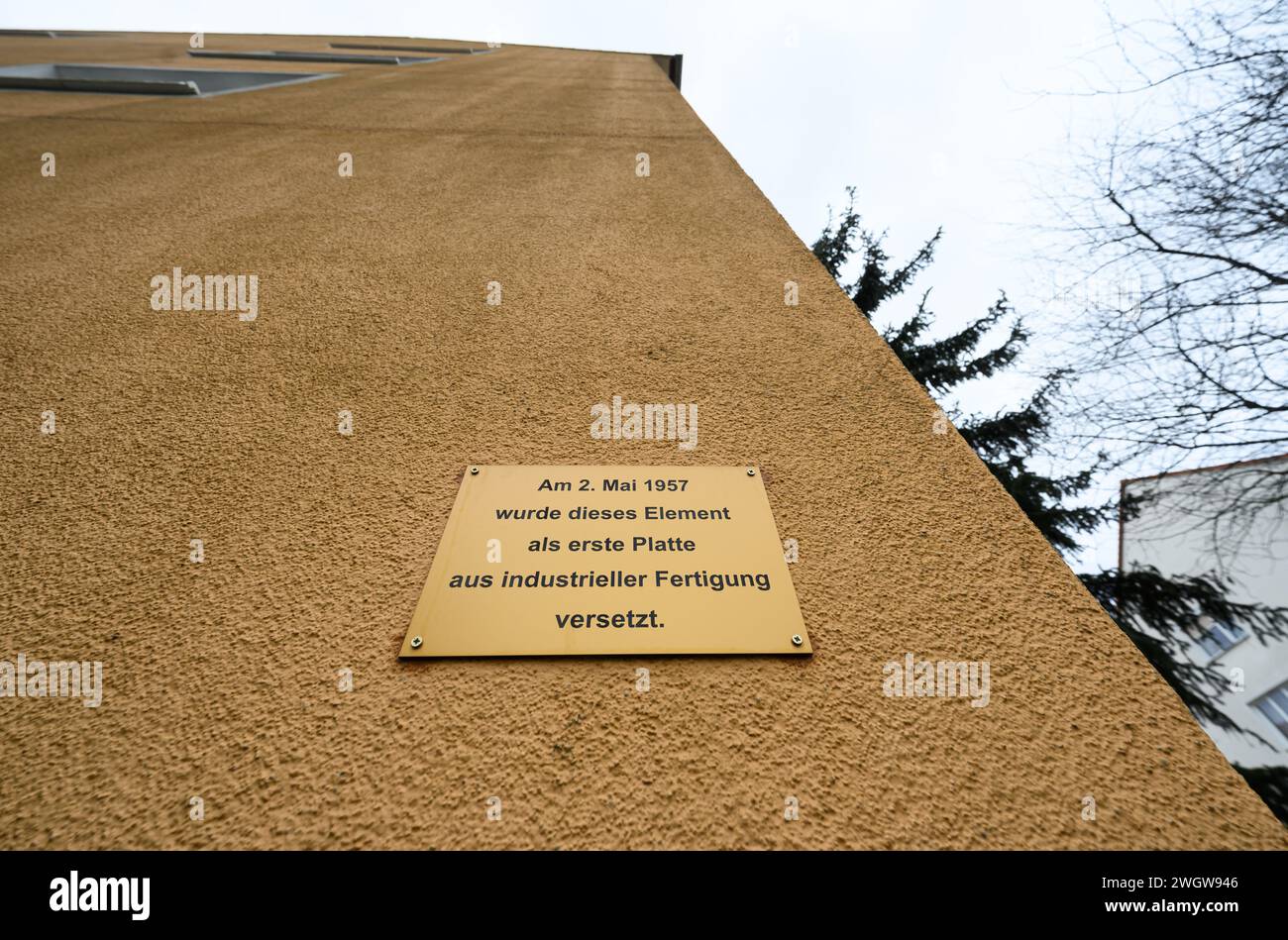 Hoyerswerda, Deutschland. Februar 2024. An der Fassade eines denkmalgeschützten Wohnblocks in der Konrad-Zuse-Straße im Wohnkomplex I (WK I) befindet sich ein Schild mit der Aufschrift „am 2. Mai 1957 wurde dieses Element als erste Platte aus der industriellen Produktion verlegt“. Der kommunale Wohnungsbauverband plant den Abriss von zwei Wohnblöcken im Stadtteil. Robert Michael/dpa/Alamy Live News Stockfoto