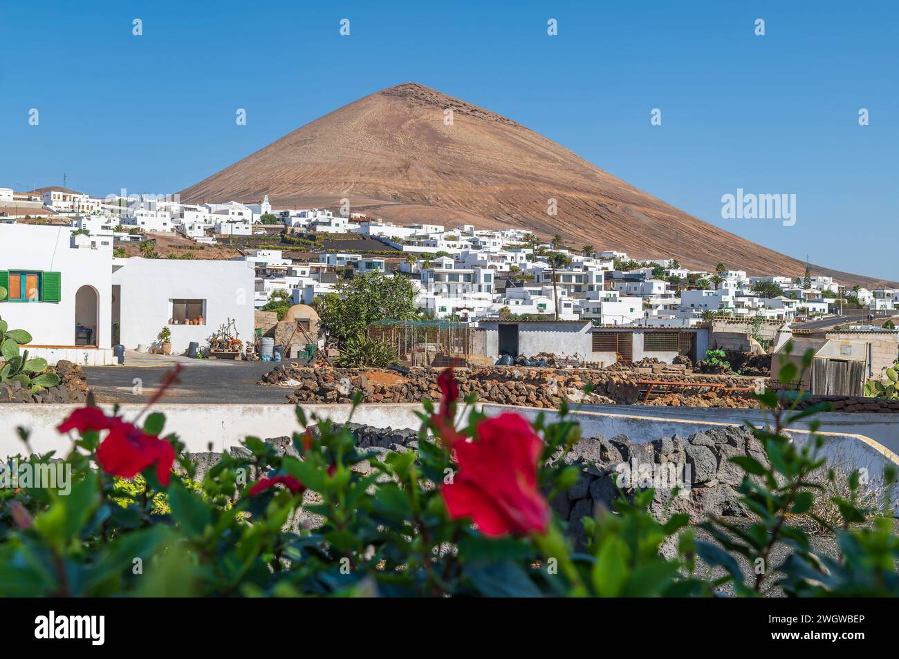 Bezaubernde Aussicht auf das Dorf Tias vor der berühmten Montaña Blanca auf Lanzarote, die das Wesen des kanarischen Lebens und der vulkanischen Landschaften einfängt. Stockfoto