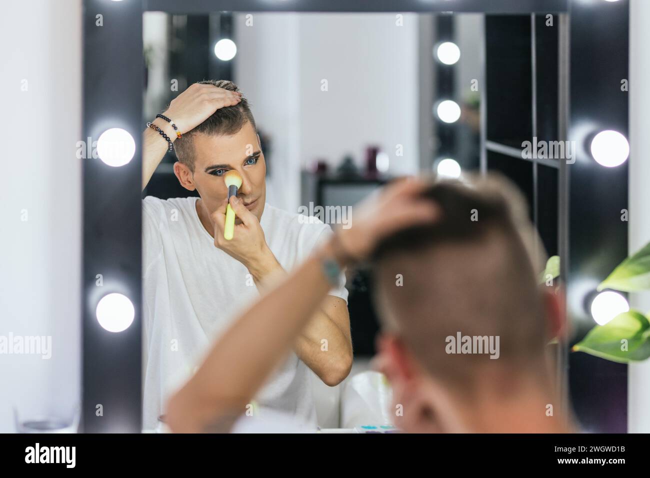 Schwuler Mann, der sich mit einer Bürste in einer Backstage ausdenkt Stockfoto