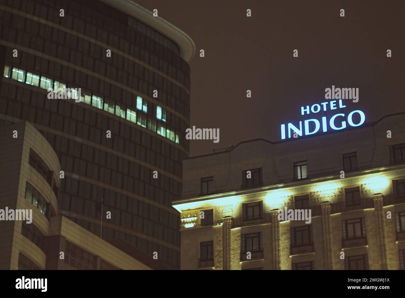Brüssel, Belgien 5. Februar 2024. Gebäudefassade mit Nachtbeleuchtung. U-Bahn-Station Roger. Architektur des Hotels Indigo mit Namen Stockfoto