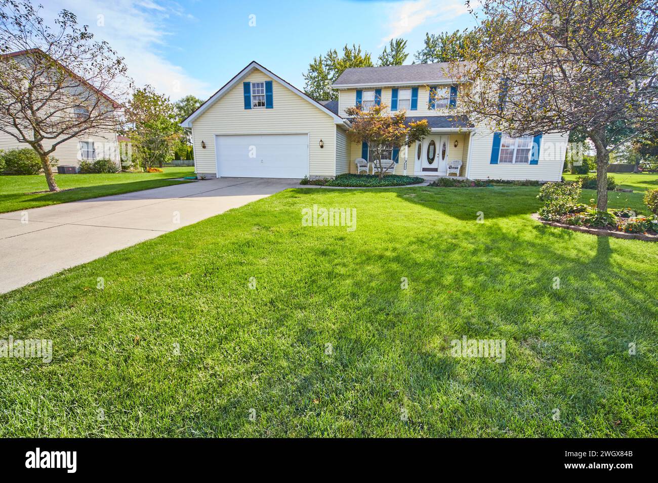 Weißes Haus im Vorort mit blauen Fensterläden und üppigem Rasen, Blick auf Augenhöhe Stockfoto