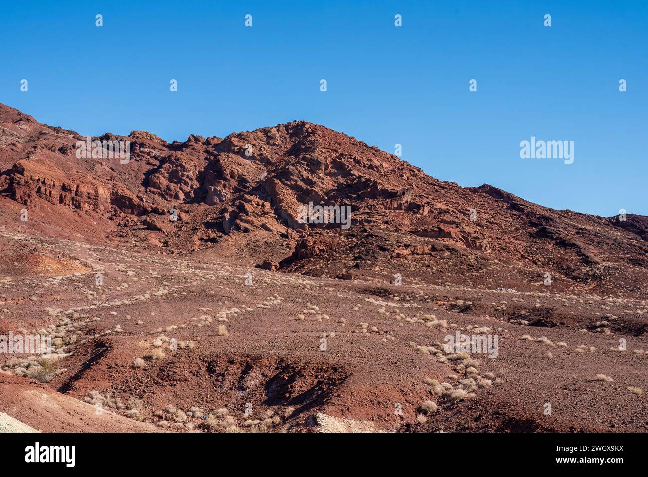 Rötlicher felsiger Hügel unter blauem Himmel Stockfoto