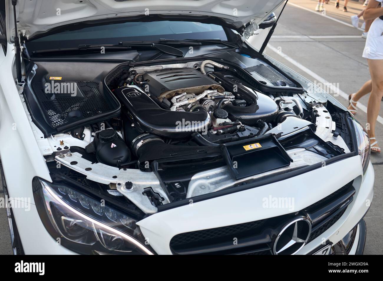 Berlin, 20. August 2022: Nahansicht des Mercedes Benz C 63 S AMG-Motors mit Carbon-Details und vielen vorbeifahrenden Beinen. Stockfoto