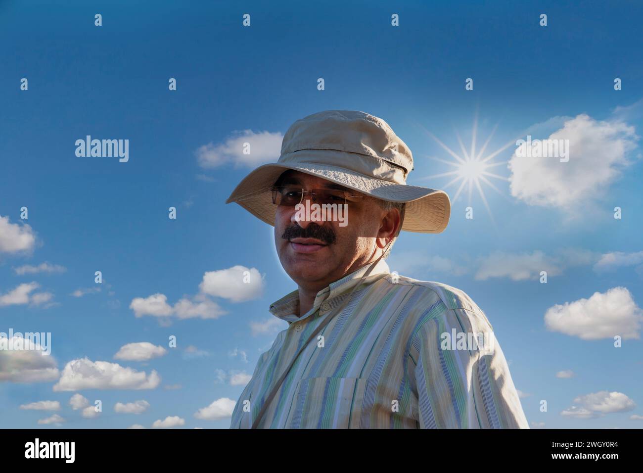 iranischer Mann draußen in der Natur Sonne und bewölktem Himmel im Hintergrund Armbanduhr Stockfoto