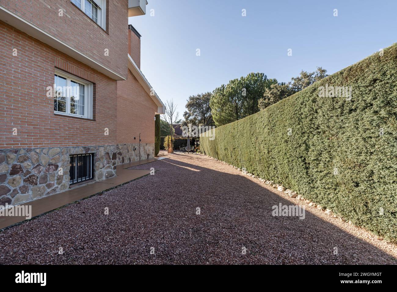 Ein Grundstück eines Hauses mit rötlichem Kies und Bäumen neben einem Schuppen Stockfoto