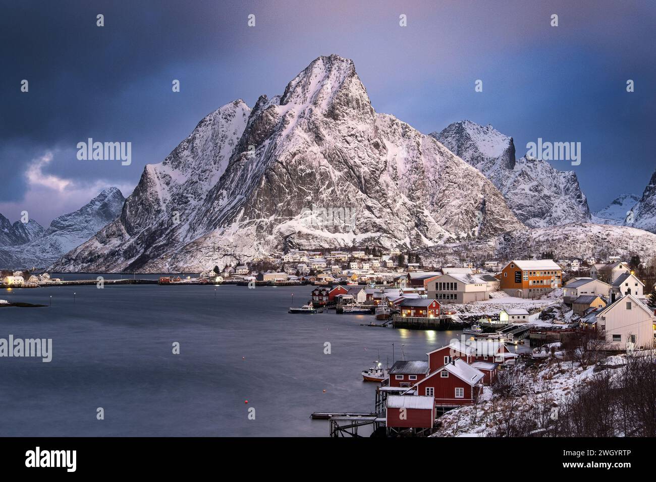 Das Fischerdorf reine und der Berg Olstinden bei Sonnenaufgang im Winter, Gemeinde Moskenes, Nordland County, Lofoten Inseln, Norwegen Stockfoto